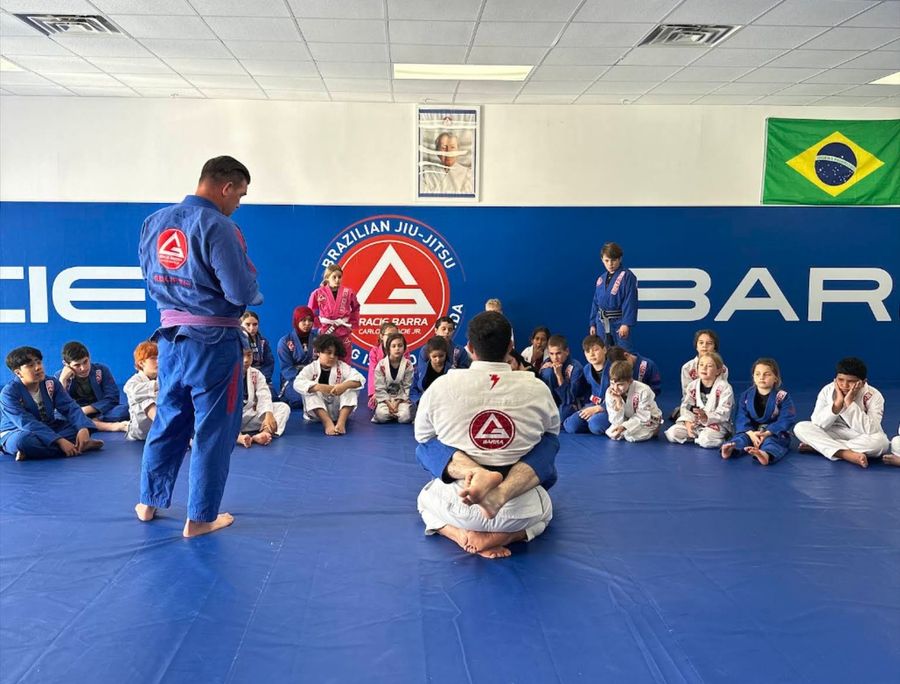 Instructors teaching a circle of young students on the mats at Gracie Barra Fleming Island